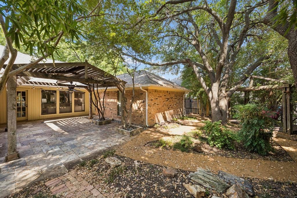The backyard features low maintenance plantings and paths under the canopy of the mature trees.