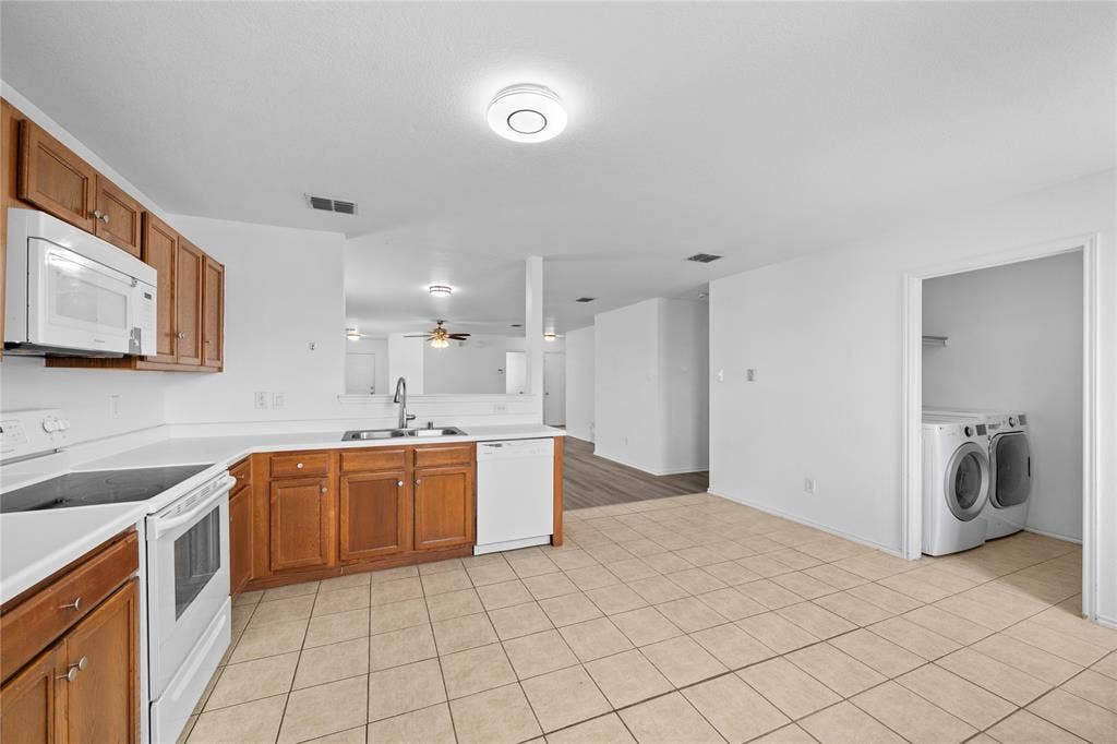 8421 Cotton Valley Lane, Arlington, TX 76002 Kitchen featuring wood cabinetry, white countertops, built-in microwave, and tile flooring