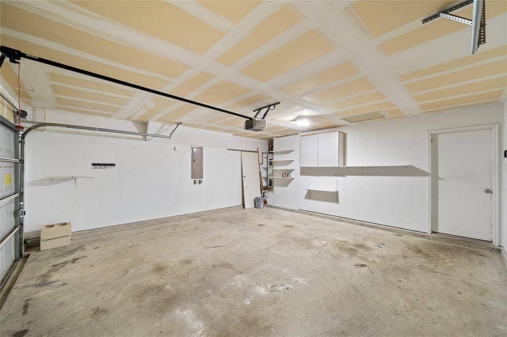 8421 Cotton Valley Lane, Arlington, TX 76002 Garage with concrete flooring, overhead lighting, and built-in white cabinetry