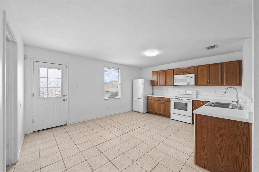 8421 Cotton Valley Lane, Arlington, TX 76002 Kitchen featuring wood-finish cabinetry, white countertops, tile flooring, and white appliances