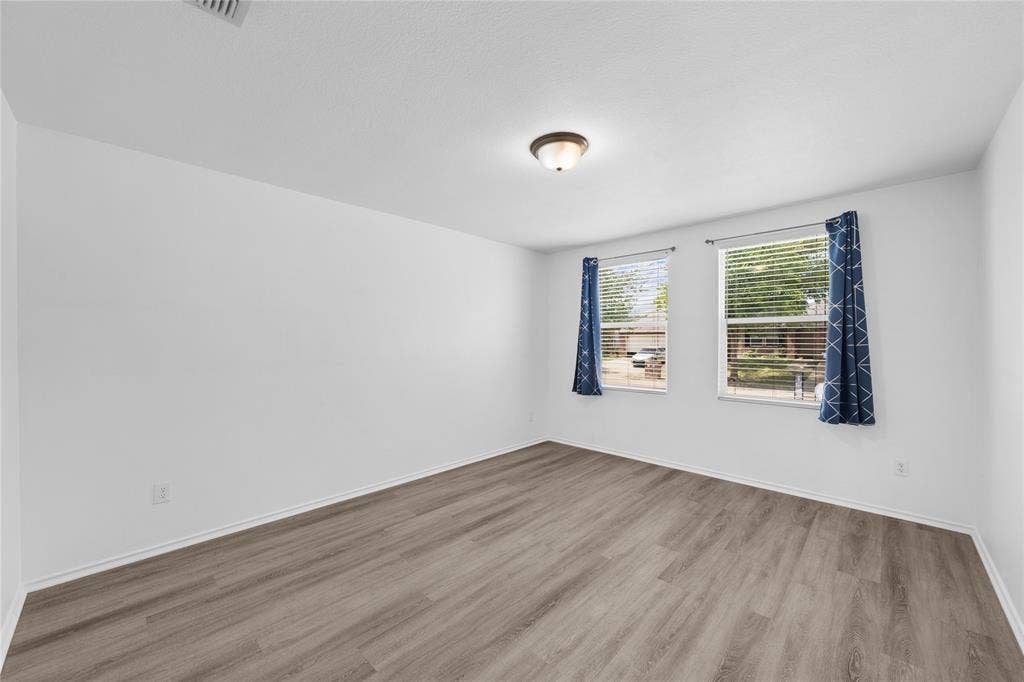8421 Cotton Valley Lane, Arlington, TX 76002 Wood-finish flooring, two windows, and a flush-mount ceiling light fixture