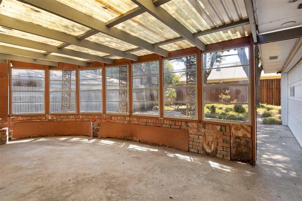 Enclosed patio with a transparent roof, concrete flooring, and brick wall accents