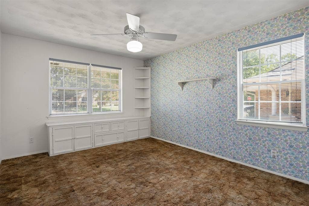 Built-in cabinetry with drawers, integrated shelving, ceiling fan with light fixture, and multiple windows