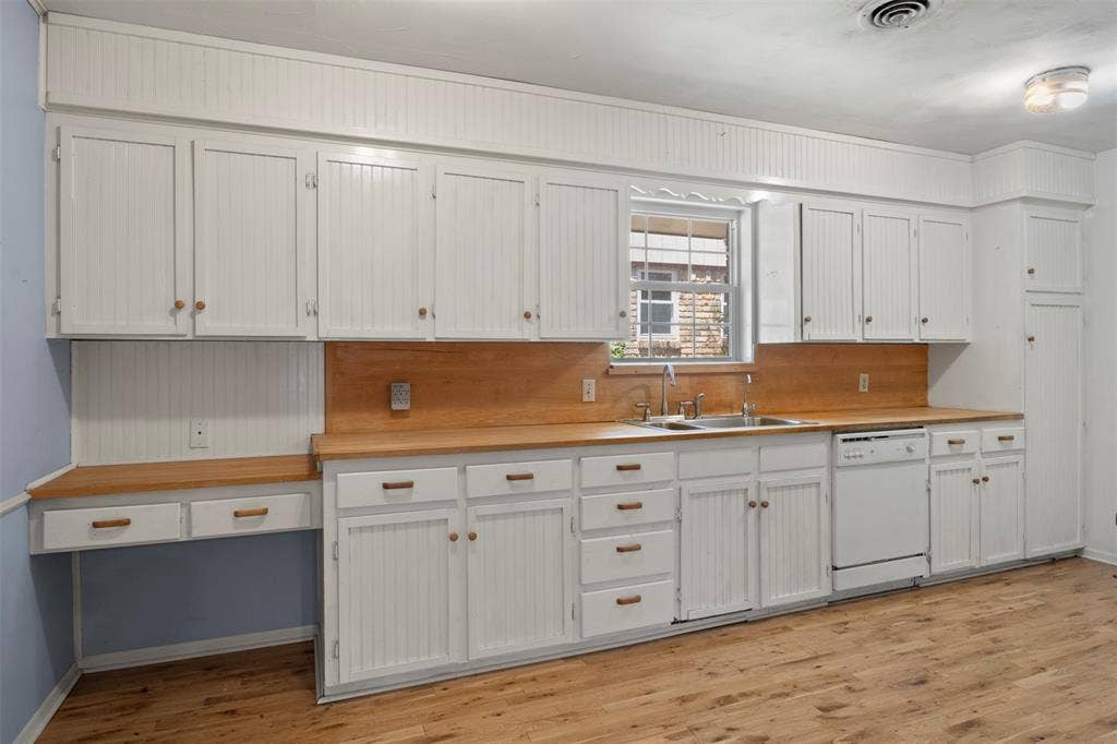 Wood-finish flooring with white cabinetry and wood countertops