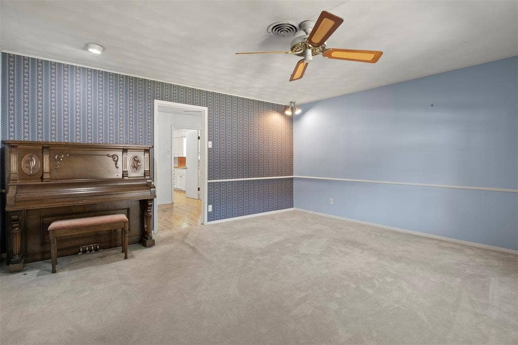 Recessed lighting, ceiling fan, textured wallpaper accent wall, wood-finish flooring visible through doorway, soft carpet