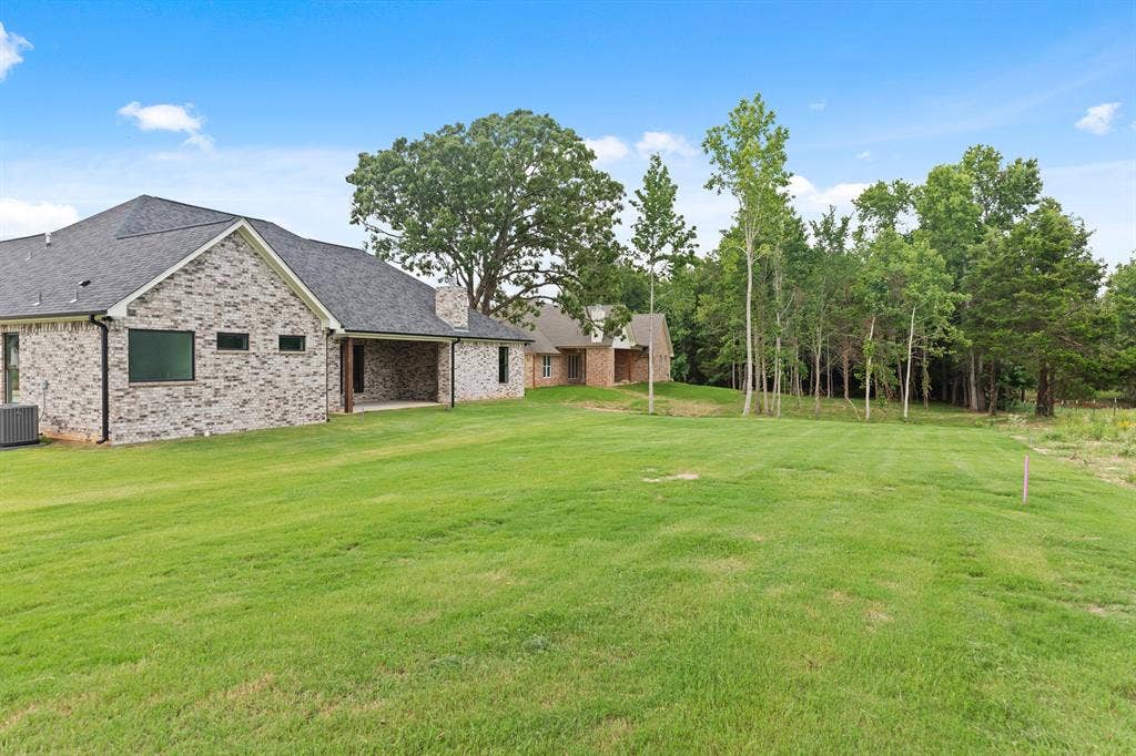 13914 Cedar Hill Lane, Tyler, TX 75704 Expansive lawn with mature trees and a brick exterior home featuring a covered patio