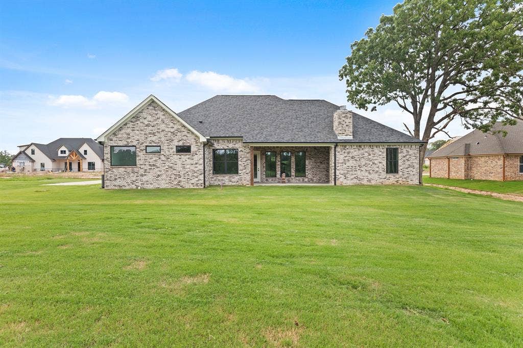 13914 Cedar Hill Lane, Tyler, TX 75704 Expansive backyard with a manicured lawn, brick exterior, covered patio, and large windows