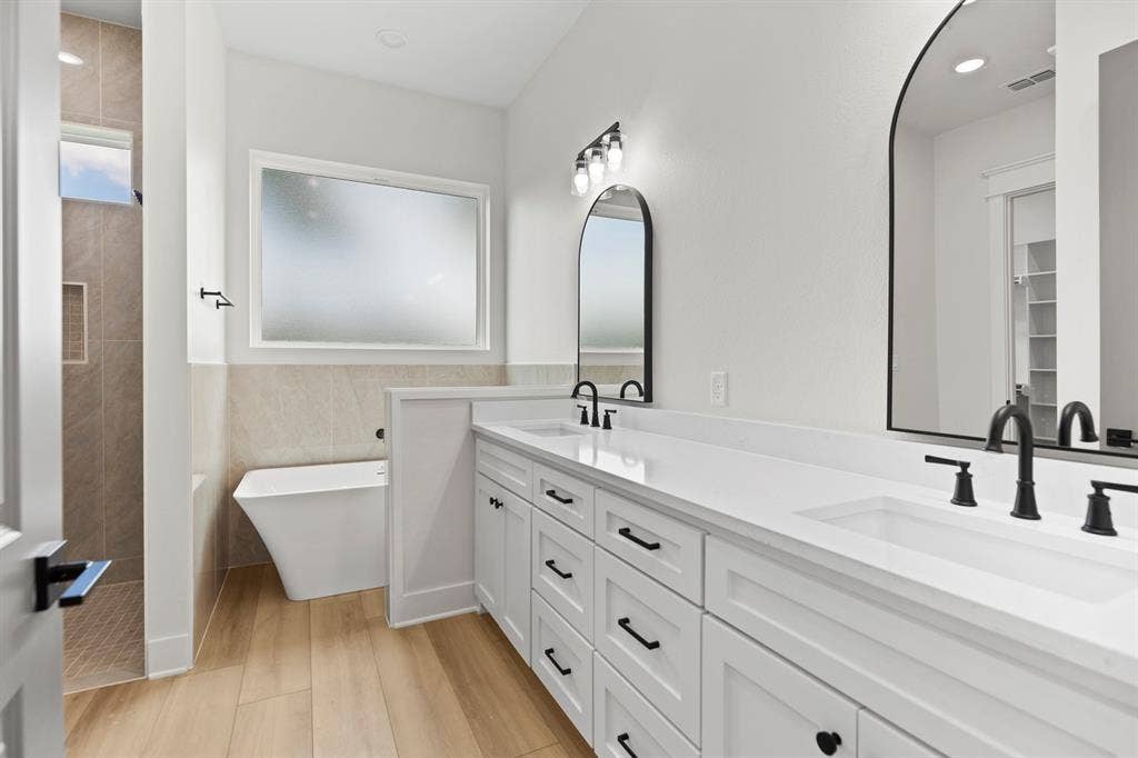 13914 Cedar Hill Lane, Tyler, TX 75704 Double vanity with integrated sinks, white cabinetry, matte black hardware, and arched mirrors