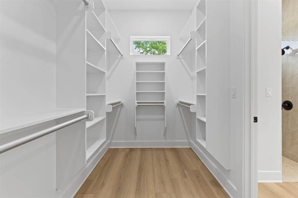13914 Cedar Hill Lane, Tyler, TX 75704 Walk-in closet with extensive built-in shelving, multiple hanging rods, wood-finish flooring, and a transom window