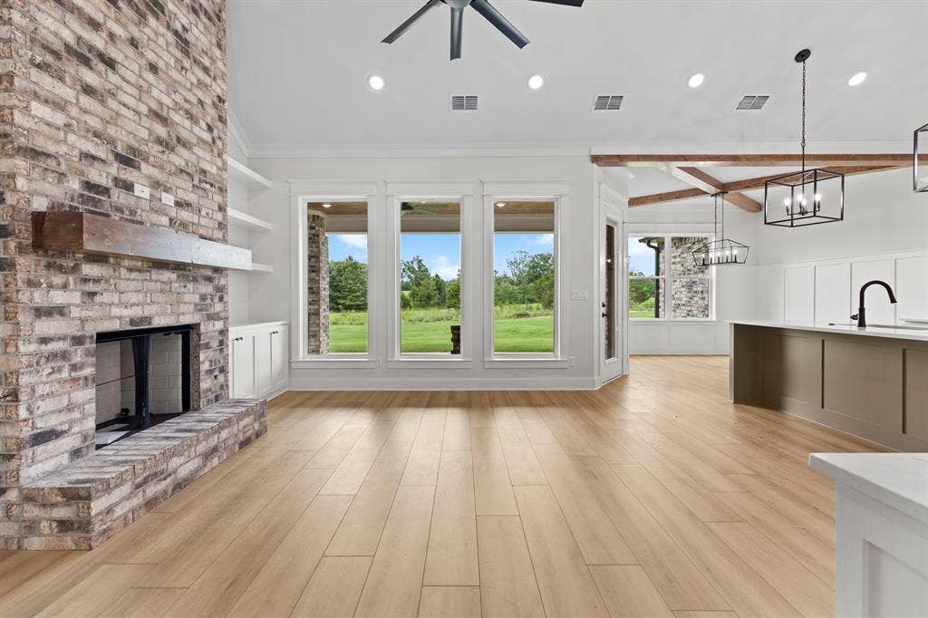 13914 Cedar Hill Lane, Tyler, TX 75704 Brick-faced fireplace with a wood mantel, built-in shelving, wood-finish flooring, and exposed ceiling beams