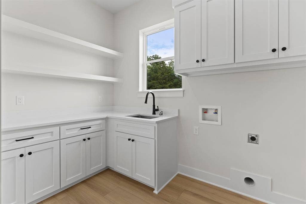 13914 Cedar Hill Lane, Tyler, TX 75704 White shaker-style cabinetry, floating open shelving, light-toned wood-finish flooring, undermount sink with a matte black faucet, and white countertops