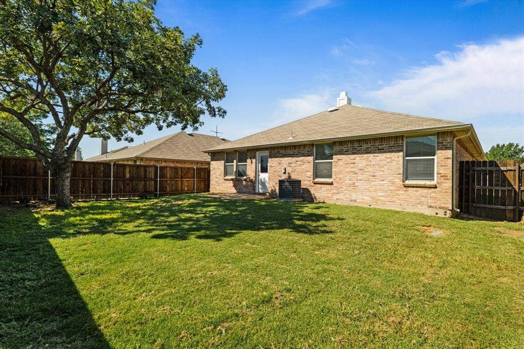 12856 Gillon Drive, Frisco, TX 75035 Back of house with brick siding, roof with shingles, a fenced backyard, and a chimney