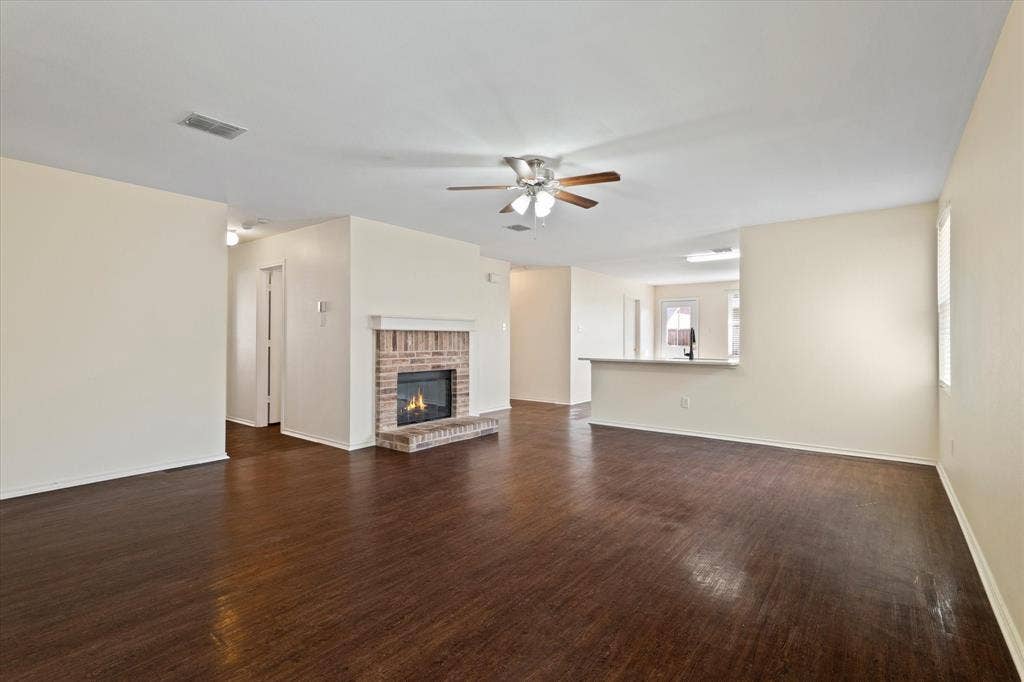 12856 Gillon Drive, Frisco, TX 75035 Unfurnished living room featuring a ceiling fan, dark wood finished floors, and a fireplace