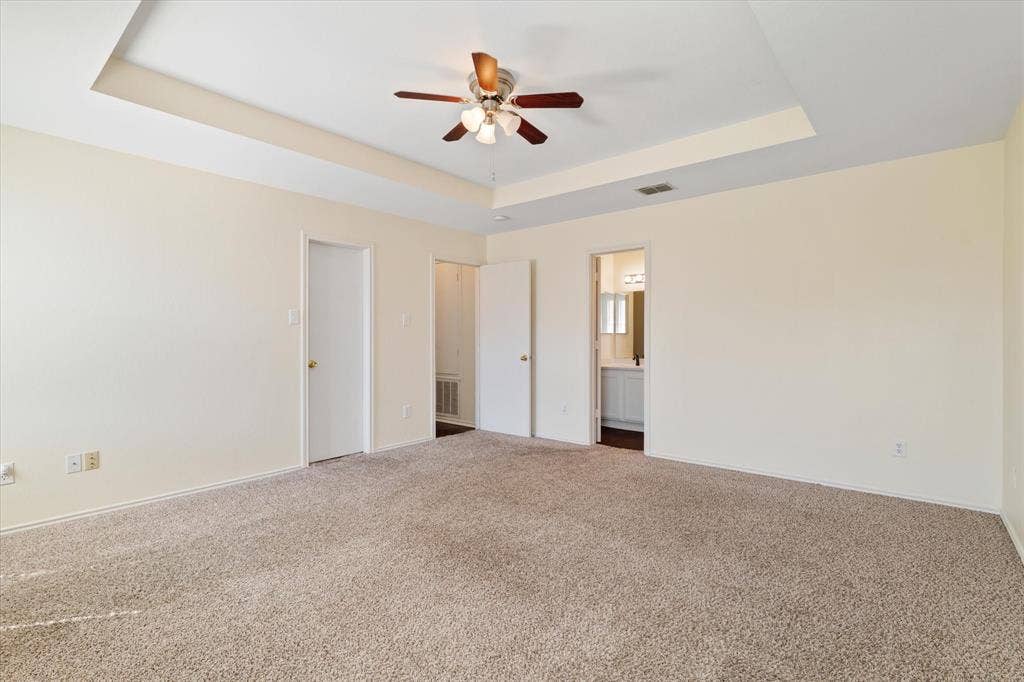 12856 Gillon Drive, Frisco, TX 75035 Unfurnished bedroom with a raised ceiling, carpet, connected bathroom, and ceiling fan