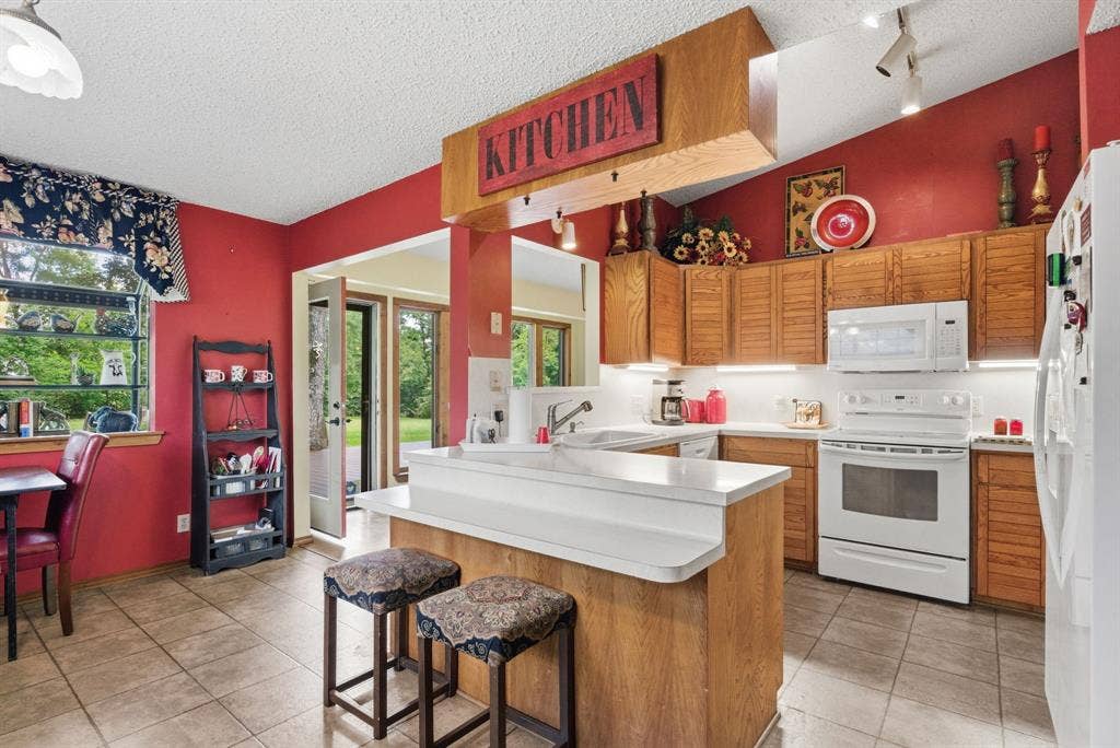 6146 County Road 334, Tyler, TX 75708 Kitchen featuring wood cabinetry, white appliances, a center island with bar seating, and tile flooring