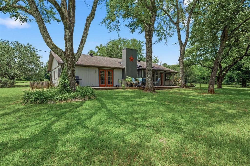 6146 County Road 334, Tyler, TX 75708 Expansive rear lawn with mature trees, a wood deck, and French doors