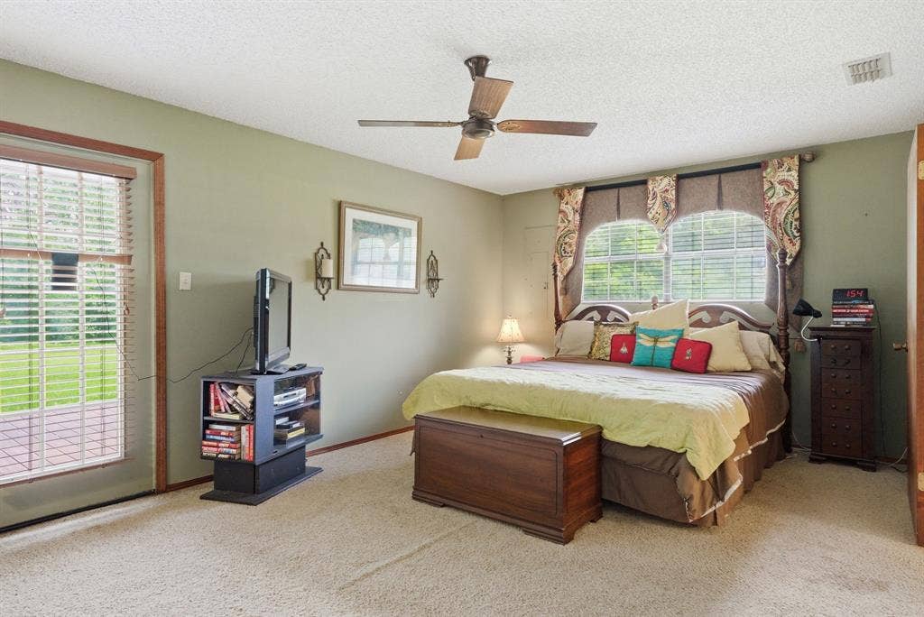 6146 County Road 334, Tyler, TX 75708 Ceiling fan with light fixture, carpeted flooring, direct access to outdoor patio space, and multiple windows with blinds