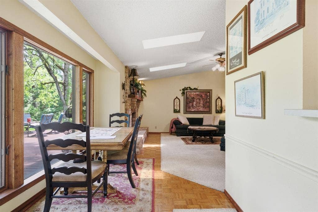 6146 County Road 334, Tyler, TX 75708 Expansive windows with wood trim, sloped ceiling with skylights, stone fireplace with hearth, and parquet wood flooring