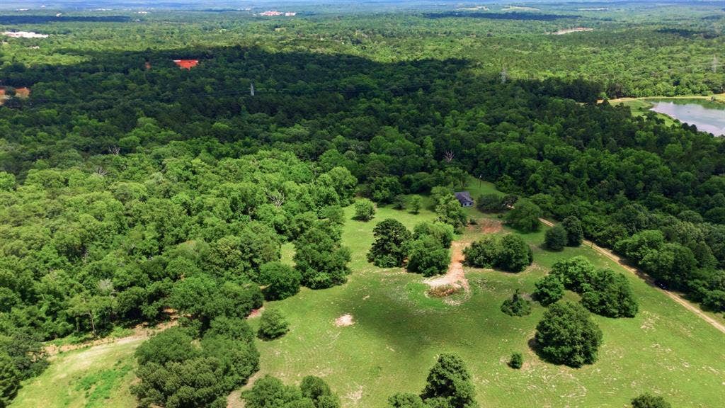 6146 County Road 334, Tyler, TX 75708 Expansive rural landscape with a residence, mature trees, and a distant body of water