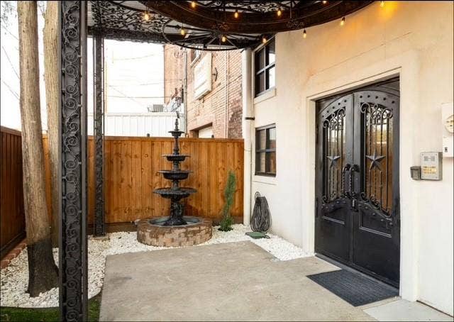 115 E Moore Avenue, #203, Terrell, TX 75160 Wrought iron double entry doors with star accents, a multi-tiered fountain feature, and a wood plank privacy fence