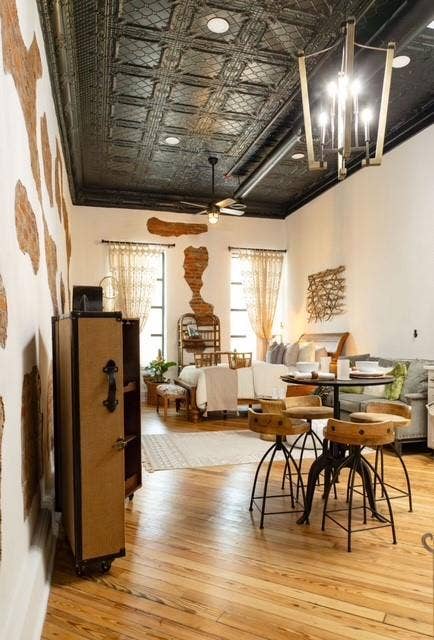 115 E Moore Avenue, #203, Terrell, TX 75160 Exposed brick wall accents, wood-finish flooring, a decorative metal ceiling, recessed lighting, and a contemporary chandelier