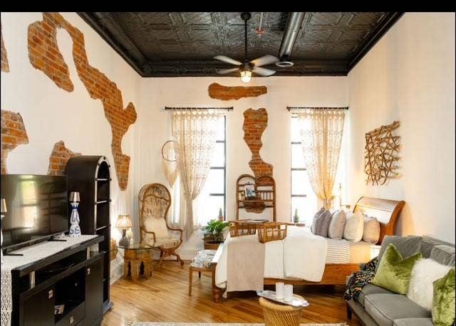 115 E Moore Avenue, #203, Terrell, TX 75160 Exposed brick wall accents, pressed tin ceiling, wood-finish flooring, industrial-style ceiling fan, and large windows with transom details
