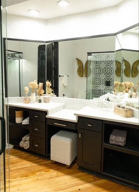 115 E Moore Avenue, #203, Terrell, TX 75160 Dual vanity with white countertops, dark wood cabinetry, wood-finish flooring, recessed lighting, and a glass-enclosed shower with patterned tile