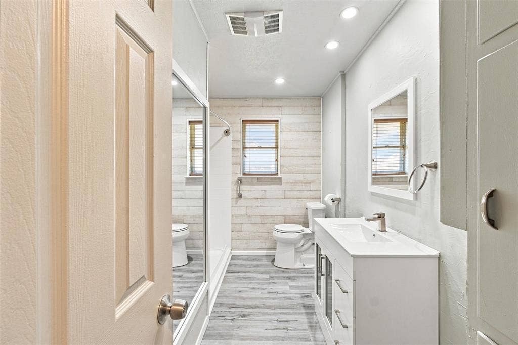 2022 Normandy Drive, Irving, TX 75060 Modern bathroom featuring wood-finish flooring, a white vanity with integrated sink, recessed lighting, and a walk-in shower with glass enclosure