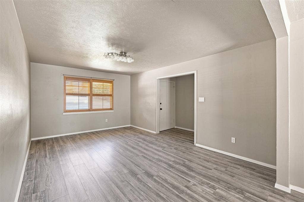 2022 Normandy Drive, Irving, TX 75060 Wood-finish flooring, neutral wall tones, window with natural wood blinds, contemporary ceiling light fixture, and white trim throughout