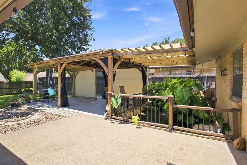 2022 Normandy Drive, Irving, TX 75060 Expansive concrete patio with a wooden pergola featuring a retractable canopy, decorative pond, integrated lighting, and privacy screens