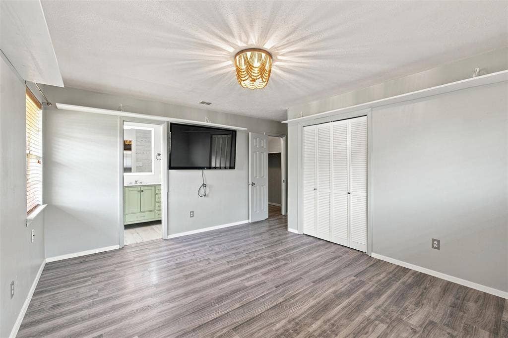 2022 Normandy Drive, Irving, TX 75060 Primary bedroom with updated flooring, statement light fixture, and direct access to the ensuite bath.