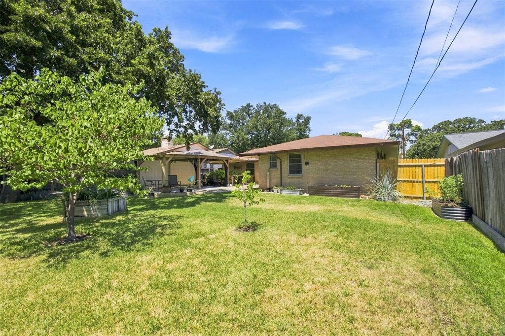 2022 Normandy Drive, Irving, TX 75060 Expansive green lawn with mature trees and a covered patio structure