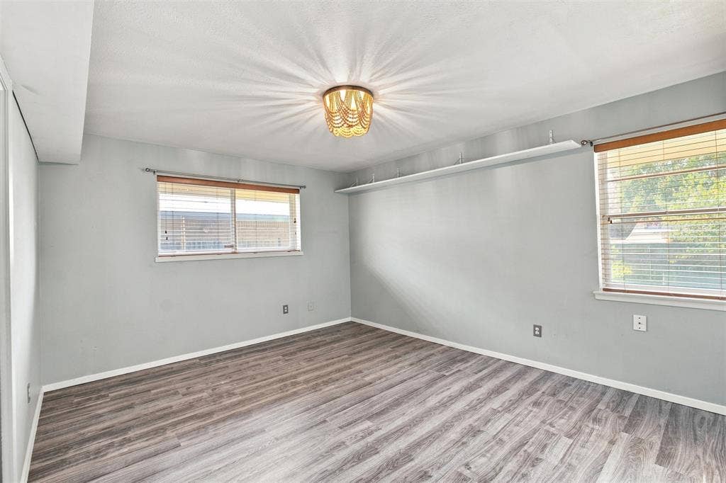 2022 Normandy Drive, Irving, TX 75060 Spacious primary bedroom featuring updates flooring, abundant natural light and a distinctive light fixture.