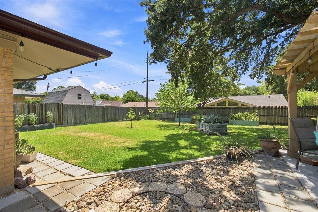 2022 Normandy Drive, Irving, TX 75060 Expansive backyard featuring a lush lawn, privacy fencing, multiple raised garden beds, and two distinct patio areas