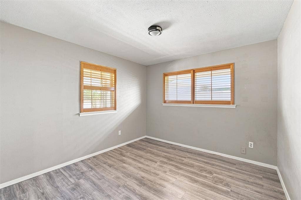 2022 Normandy Drive, Irving, TX 75060 Wood-finish flooring, neutral wall tones, two windows with wood blinds, and a flush mount ceiling light