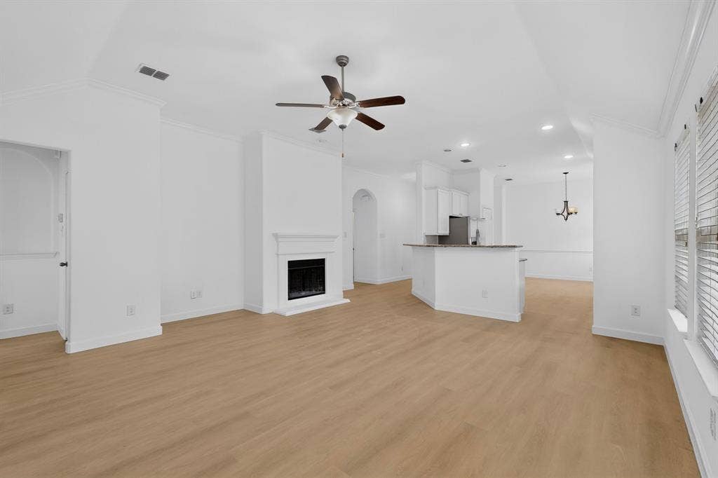 Vaulted ceilings, wood-finish flooring, fireplace with a mantle, recessed lighting, and a kitchen peninsula with cabinetry