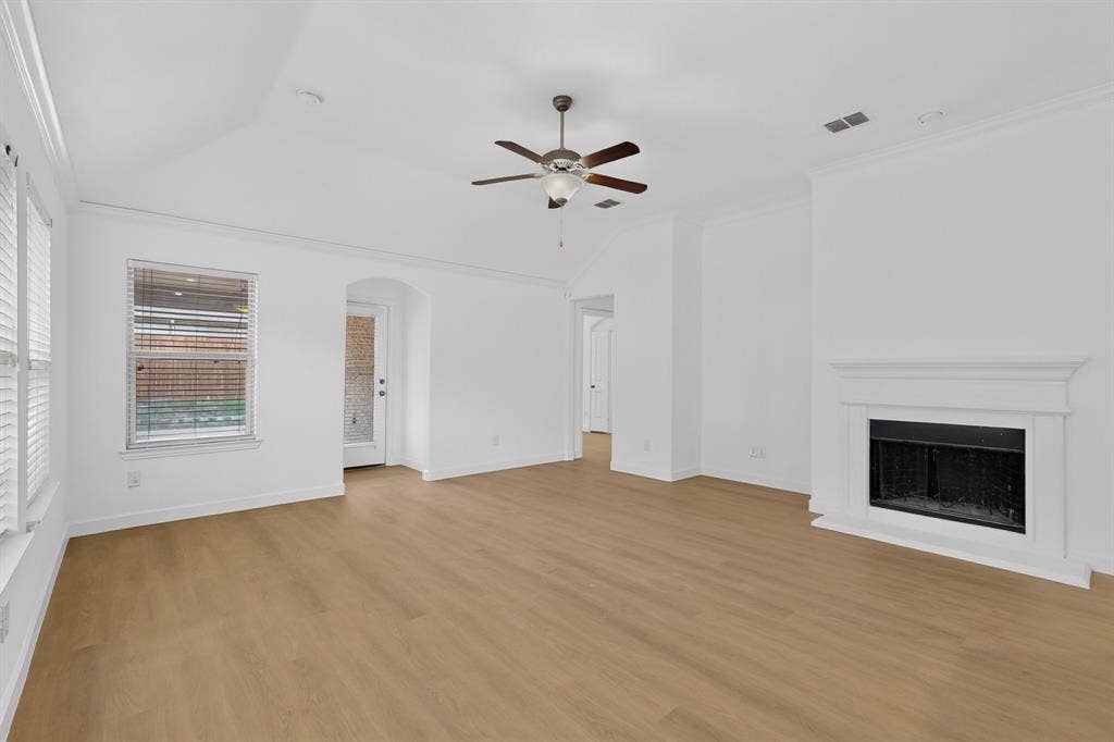 Vaulted ceilings, wood-finish flooring, white fireplace mantel, ceiling fan, and multi-pane windows