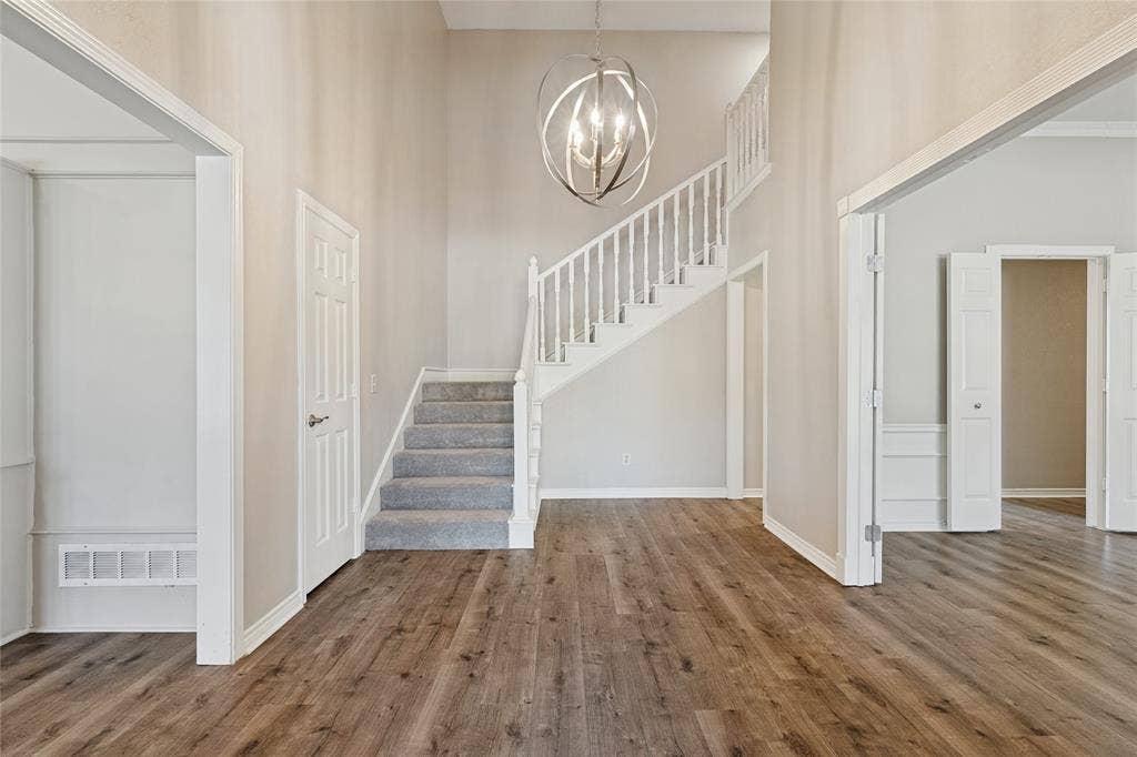 5013 Country Place Drive, Plano, TX 75023 Expansive entryway featuring wood-finish flooring, a contemporary chandelier, a staircase with white balusters and carpeted treads, and paneled interior doors