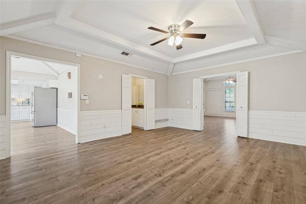 5013 Country Place Drive, Plano, TX 75023 Wood-finish flooring, tray ceiling with recessed lighting, ceiling fan, shiplap wall accent, and bi-fold doors