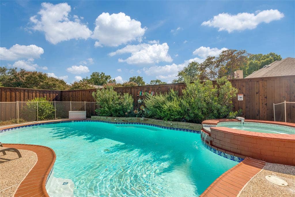 5013 Country Place Drive, Plano, TX 75023 Backyard oasis featuring a swimming pool, integrated hot tub with waterfall, flagstone coping, and a 12' new cedar privacy fence