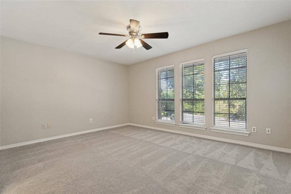 5013 Country Place Drive, Plano, TX 75023 Large upstairs bedroom with the Jack & Jill attached bathroom, has Neutral-toned carpeting, three large windows with blinds, and a ceiling fan with integrated lighting