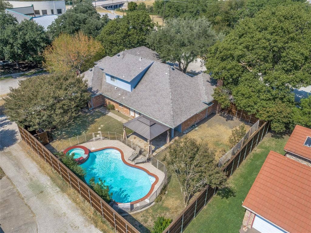 5013 Country Place Drive, Plano, TX 75023 Aerial view showcasing a custom-shaped resort-style swimming pool with integrated spa, surrounded by mature landscaping and wooden fencing