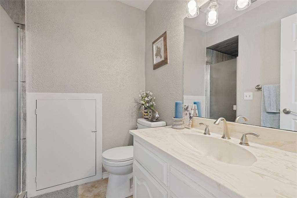 5013 Country Place Drive, Plano, TX 75023 Upstairs ensuite bath, with Vanity with an integrated sink, brushed nickel faucet, and a large mirror, and a walk in shower with custom porcelain tile.