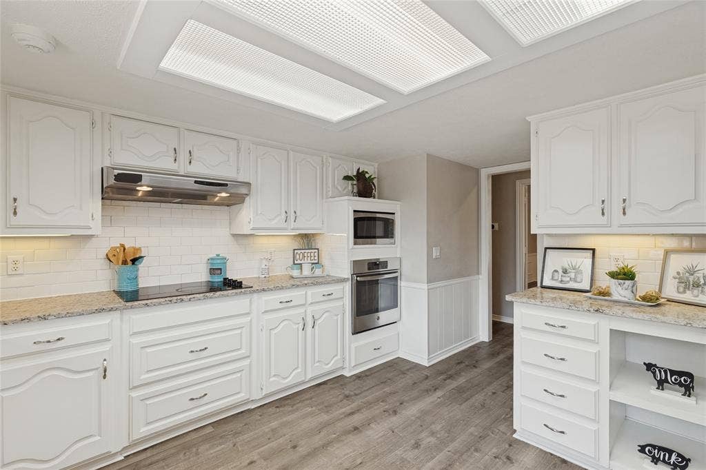 5013 Country Place Drive, Plano, TX 75023 White cabinetry with decorative hardware, granite countertops, stainless steel appliances, and wood-finish flooring
