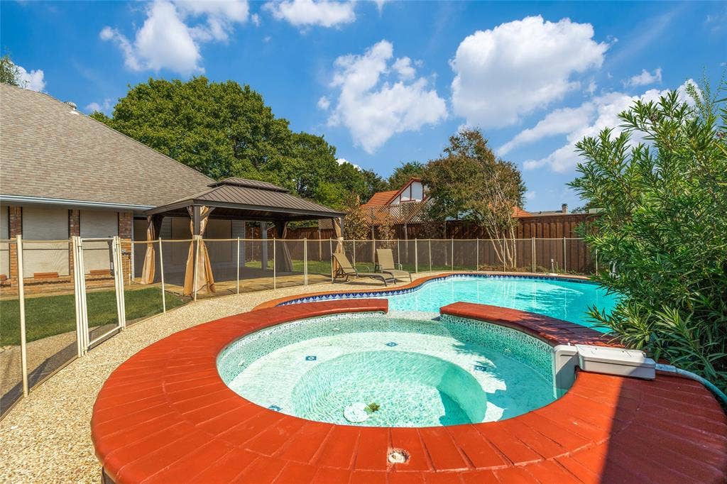 5013 Country Place Drive, Plano, TX 75023 Sparkling integrated spa with a red brick coping, a surrounding safety fence, gorgeous flower bed