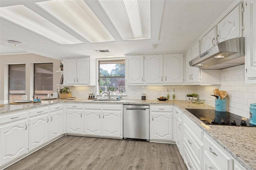 5013 Country Place Drive, Plano, TX 75023 White cabinetry, granite countertops, subway tile backsplash, stainless steel dishwasher, and a built-in cooktop