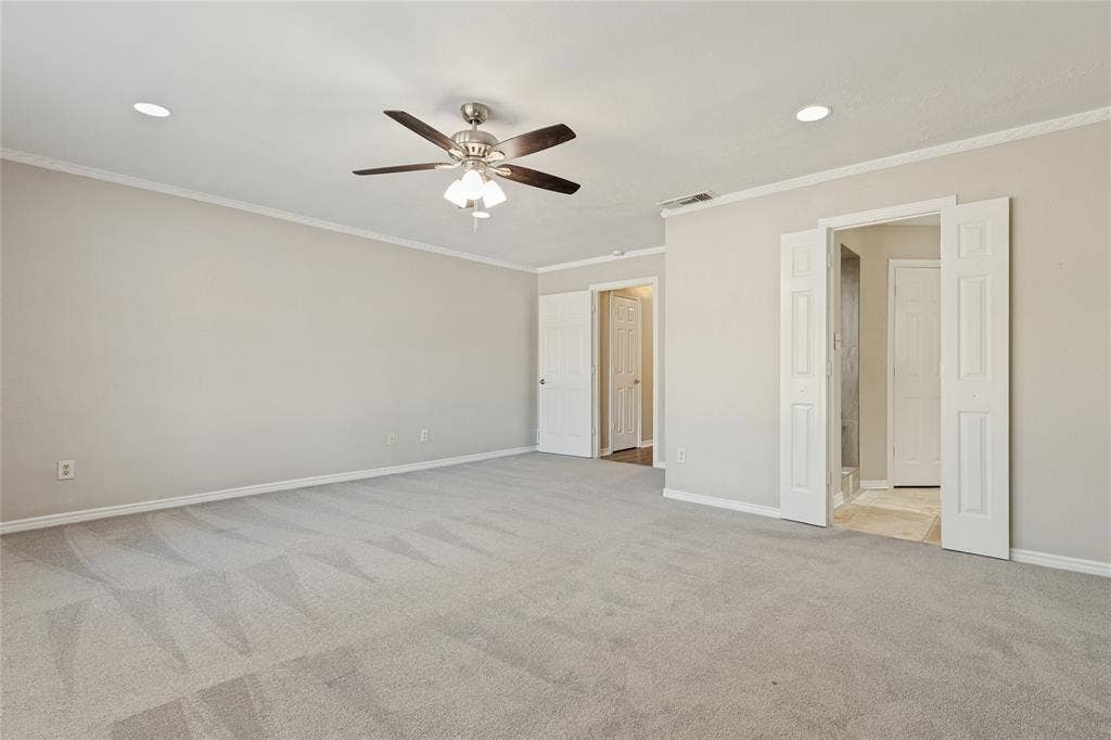 5013 Country Place Drive, Plano, TX 75023 Spacious primary bedroom featuring neutral carpet, recessed lighting, a ceiling fan, and crown molding, large windows, and an ensuite bath