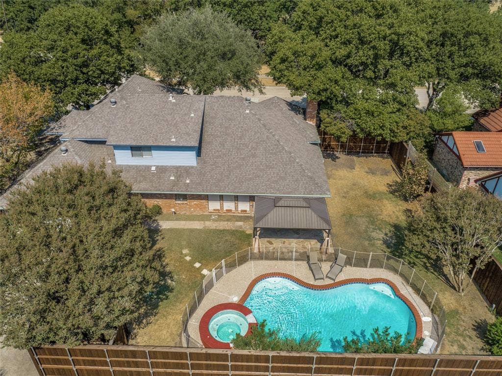 5013 Country Place Drive, Plano, TX 75023 Kidney-shaped swimming pool with an integrated spa, surrounded by a safety fence