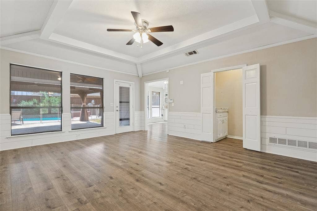 5013 Country Place Drive, Plano, TX 75023 Wood-finish flooring, white shiplap wainscoting, a tray ceiling with a ceiling fan, and large windows with outdoor access to the cabana and pool view. Dry bar with tiffany light fixture.