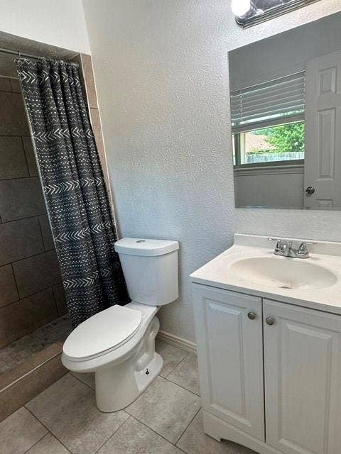 1441 Quartet Drive, Dallas, TX 75241 Tiled shower surround, white toilet, single vanity with integrated sink, chrome faucet, and tiled flooring